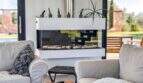 Modernes Wohnzimmer der Luxusfinca mit elegantem Glaskamin, Loungessofas und Blick in den mediterranen Garten.