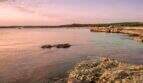 Felsige Meeresküste bei Sonnenuntergang mit ruhigem Wasser, Blick auf Ses Salines, Mallorca