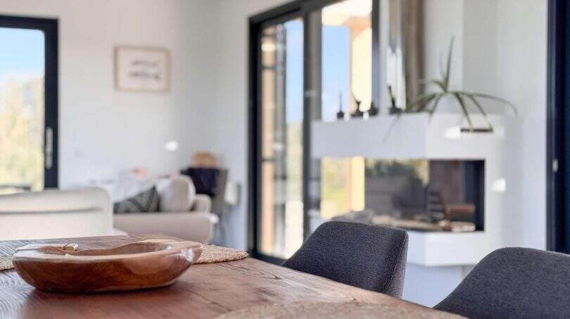 Offener Wohn-Essbereich der Luxusfinca mit Kamin, Holztisch und Blick zur Terrasse in Ses Salines