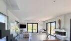 Helles Wohnzimmer der Luxusfinca mit Kamin, weißen Sofas und Panoramafenstern mit Naturblick.