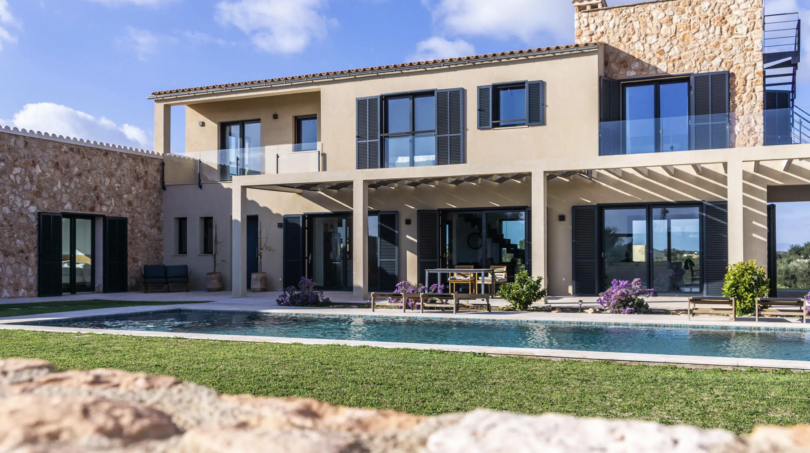 Luxusfinca Ses Salines: Außenpool, Pergola & mediterrane Steinfassade unter blauem Himmel