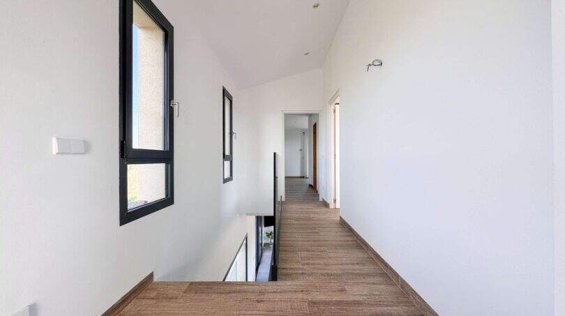 Heller Flur mit Holzboden, weißen Wänden und modernem Treppengeländer in mediterraner Luxusfinca in Ses Salines