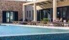 Luxusfinca Ses Salines: Pool mit Natursteinmauer, Holzliegen und überdachter Terrasse mit Blumenbeeten.