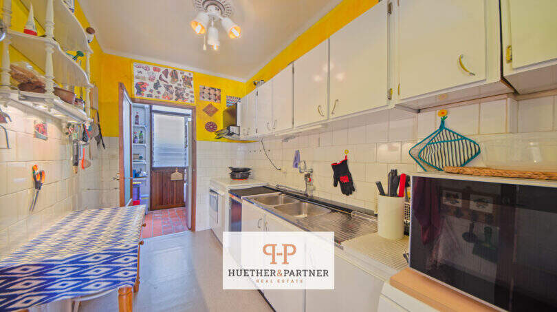Cocina del apartamento de Mallorca en Porto Cristo con paredes amarillas, armarios blancos y doble fregadero
