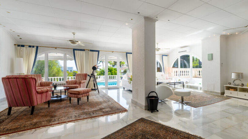 Helles Wohnzimmer der Poolvilla in Cala Murada mit Marmorboden, Orientteppichen und Blick auf den Pool.