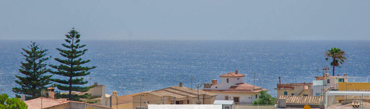 Vista exterior de la urbanización Porto Cristo con vistas al mar, casas mediterráneas con tejados de terracota y exuberante vegetación