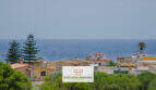 Vista exterior de la urbanización Porto Cristo con vistas al mar, casas mediterráneas con tejados de terracota y exuberante vegetación