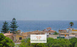 Außenansicht Wohnanlage Porto Cristo mit Meerblick, mediterrane Häuser mit Terrakottadächern und üppiger Vegetation