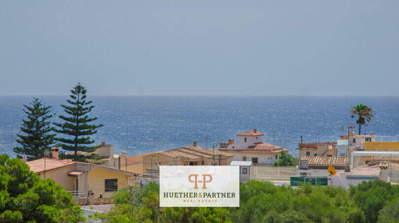 Vista exterior de la urbanización Porto Cristo con vistas al mar, casas mediterráneas con tejados de terracota y exuberante vegetación