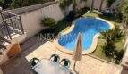 Außenbereich des Ferienhauses in Muro mit Pool, Gartenanlage und überdachter Terrasse mit Sitzgruppe.