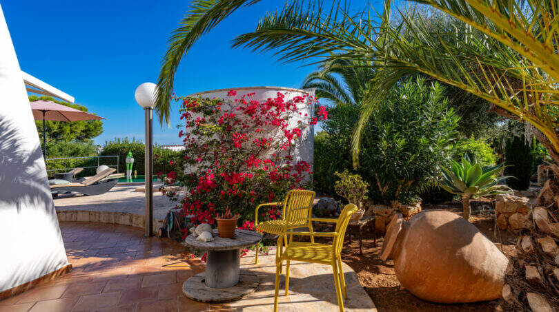Mediterranean terrace of the sea view villa in Cala Murada with yellow chairs, bougainvillea and palm trees