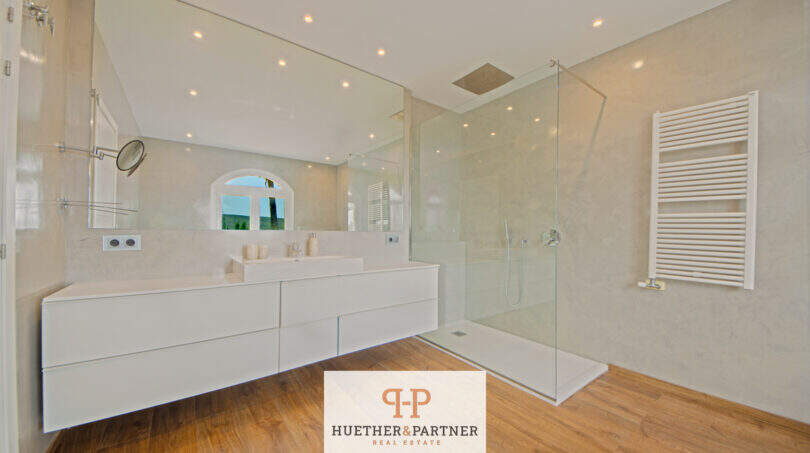 Modernes Badezimmer der Finca Santa Maria mit Doppelwaschbecken, Glasdusche und Holzboden.