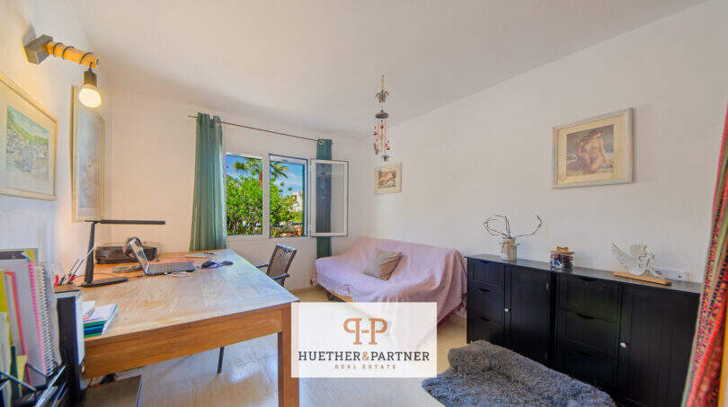 Helles Arbeitszimmer mit Holzschreibtisch, Sofa und Fenster mit Gartenblick in Haus mit Pool, Cala Murada
