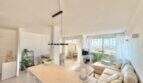 Helles Wohnzimmer mit offener Küche, modernem Sofa und Balkonzugang mit Meerblick in Palmanova