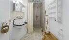 Baño luminoso con lavabo vintage, ducha, lámpara de cristal y cestas de fibra natural en la casa urbana de Felanitx