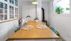 Comedor con mesa de madera, sillas azules, aparador blanco y gato sobre la mesa en la casa urbana de Felanitx