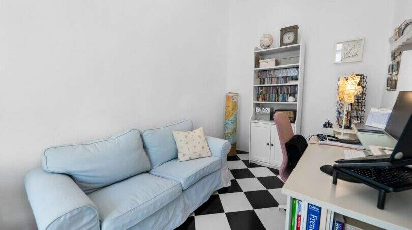 Acogedor despacho con sofá azul, piso de tablero de ajedrez y escritorio en casa urbana Felanitx