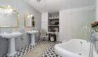 Elegante baño con lámpara de cristal, espejos dorados, bañera exenta y piso de baldosas de mosaico en casa urbana Felanitx