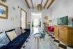 Sala de estar con sofá de terciopelo azul, piso de tablero de ajedrez, techo de vigas de madera y sillón rojo en casa urbana Felanitx