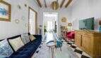 Sala de estar con sofá de terciopelo azul, piso de tablero de ajedrez, techo de vigas de madera y sillón rojo en casa urbana Felanitx