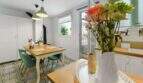 Comedor luminoso con piso de baldosas con patrón, mesa de madera, sillas turquesas y decoración floral en casa urbana Felanitx