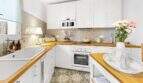 Cocina luminosa con armarios blancos, encimeras de madera, suelo de mosaico y electrodomésticos modernos en la casa urbana de Felanitx