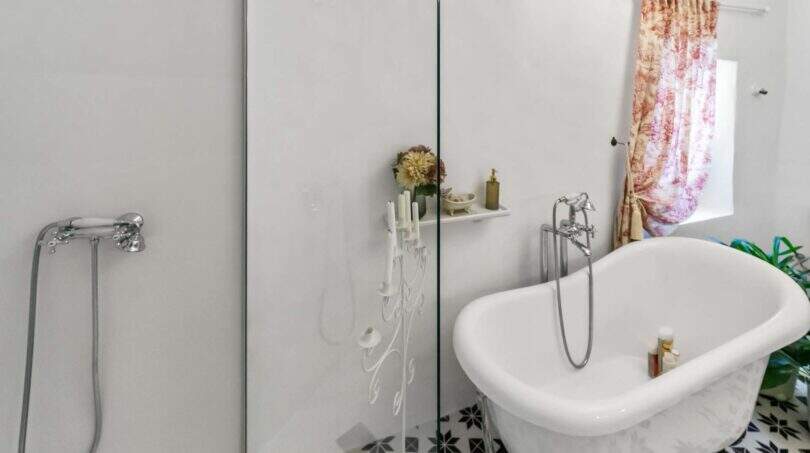 Elegante baño con bañera exenta, mampara de cristal, ducha y baldosas con patrón en casa urbana Felanitx