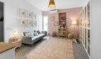 Sala de estar con sofá gris, pared de acento rosa, piso de baldosas con patrón y alfombra vintage en casa urbana Felanitx