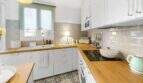 Cocina luminosa con armarios blancos, encimeras de madera, placa de cocción y baldosas de piso con patrón en casa urbana Felanitx