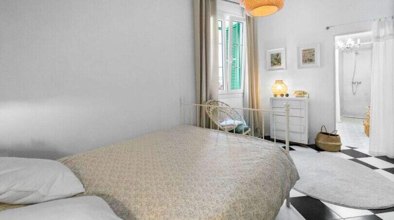 Dormitorio luminoso con cama doble, piso de tablero de ajedrez y baño en suite en casa urbana Felanitx