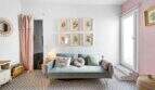 Sala de estar con sofá gris, cuadros de flores, piso de baldosas con patrón y acentos rosa en casa urbana Felanitx