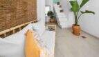 Área de estar con sofá de bambú, escalera blanca y plantas verdes en encantadora casa urbana en Felanitx