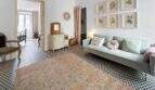 Sala de estar con sofá azul claro, cómoda vintage, cuadros de flores y piso de baldosas con patrón en casa urbana Felanitx