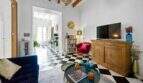 Sala de estar con piso de tablero de ajedrez, techo de vigas de madera, sofá azul, sillón rojo y aparador rústico en casa urbana Felanitx