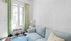 Sala de estar luminosa con sofá azul, cortinas verdes y piso de tablero de ajedrez en casa urbana Felanitx