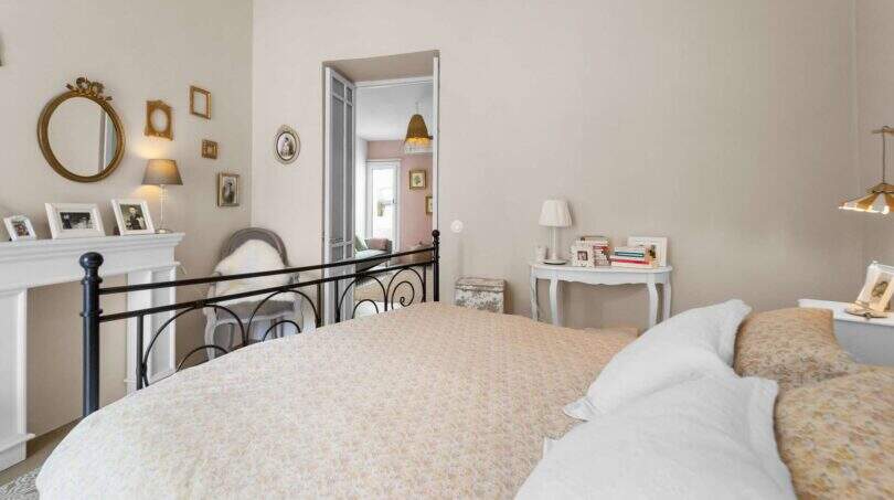 Dormitorio luminoso con cama de metal negro, repisa de chimenea blanca y espejos de pared dorados en encantadora casa urbana Felanitx