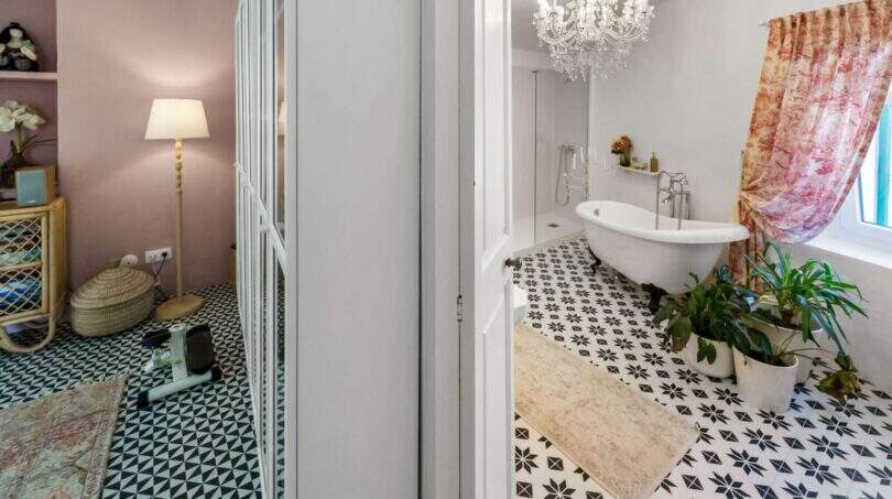 Elegante baño con bañera exenta, lámpara de araña y piso de baldosas blanco y negro en casa urbana Felanitx