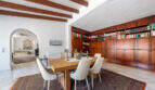 Elegantes Esszimmer mit Holzbalkendecke, großer Einbaubibliothek und Bogendurchgang in Villa Cala Murada