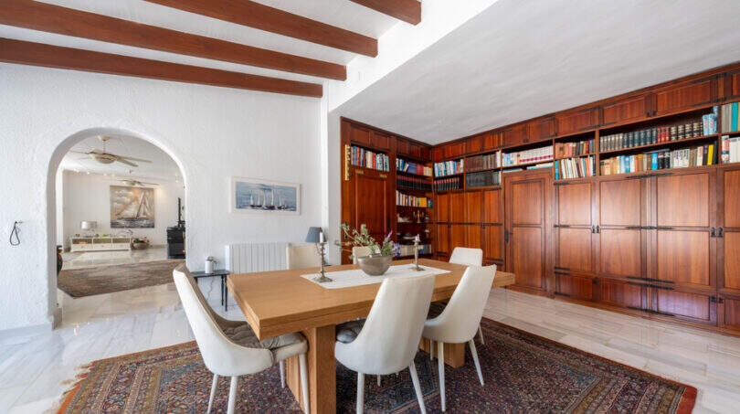 Elegantes Esszimmer mit Holzbalkendecke, großer Einbaubibliothek und Bogendurchgang in Villa Cala Murada