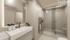 Baño moderno con ducha de cristal, toallero calefactor y espejo iluminado en el hotel-apartamento Portocolom
