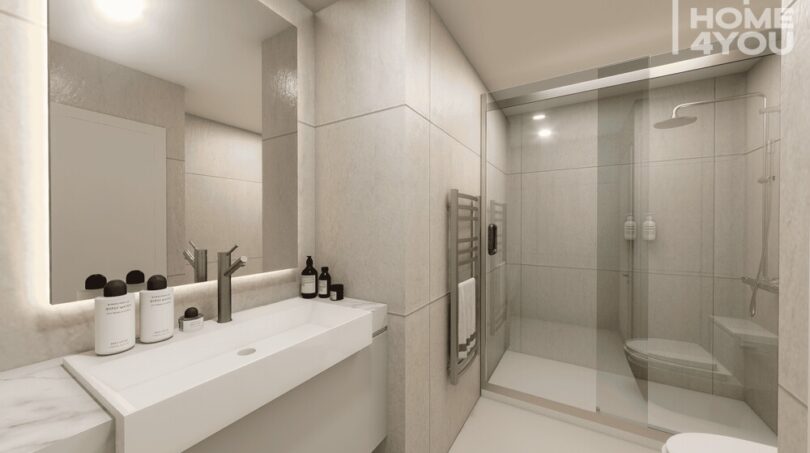 Baño moderno con ducha de cristal, toallero calefactor y espejo iluminado en el hotel-apartamento Portocolom