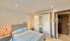 Helles Schlafzimmer mit Doppelbett, blauer Bettwäsche, Einbauschrank und Holztür in möblierter Wohnung in Pere Garau