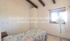 Bedroom of the Mallorca finca with single bed, white built-in wardrobe, wooden beamed ceiling and small window.