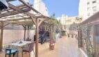 Sonnige Dachterrasse mit Holzpergola, Sitzbereich und Palmen, umgeben von Stadtgebäuden in Palma