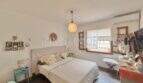 Dormitorio luminoso con cama doble, ventanas de madera y aire acondicionado en casa mediterránea en Sa Ràpita