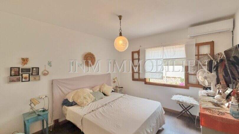 Dormitorio luminoso con cama doble, ventanas de madera y aire acondicionado en casa mediterránea en Sa Ràpita