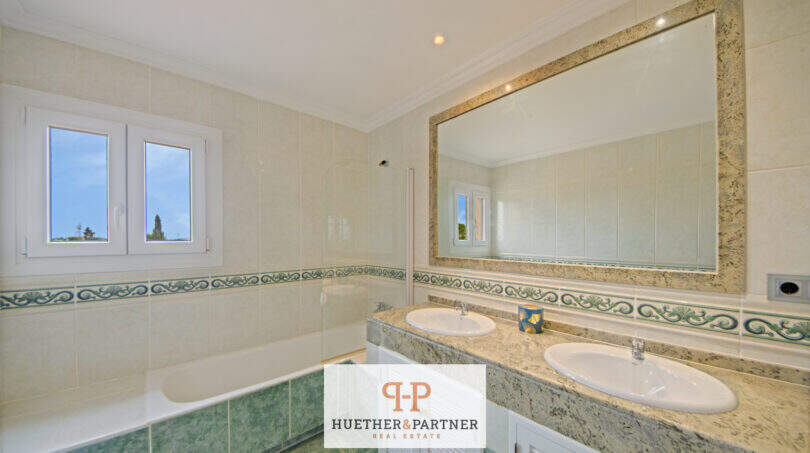Helles Badezimmer der Finca Santa Maria mit Doppelwaschbecken, Marmor-Waschtisch und Badewanne.