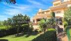 Fachada de un apartamento mediterráneo en Cala Millor con jardín privado cuidado, terraza y exuberante vegetación.