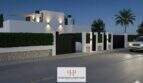 Beleuchtete Außenfassade einer modernen Neubau-Doppelhaushälfte in Cala d'Or bei Nacht mit Einfahrtstor