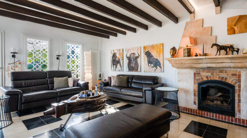 Elegant living room of the sea view villa in Cala Murada with fireplace, wooden beams and leather furnishings